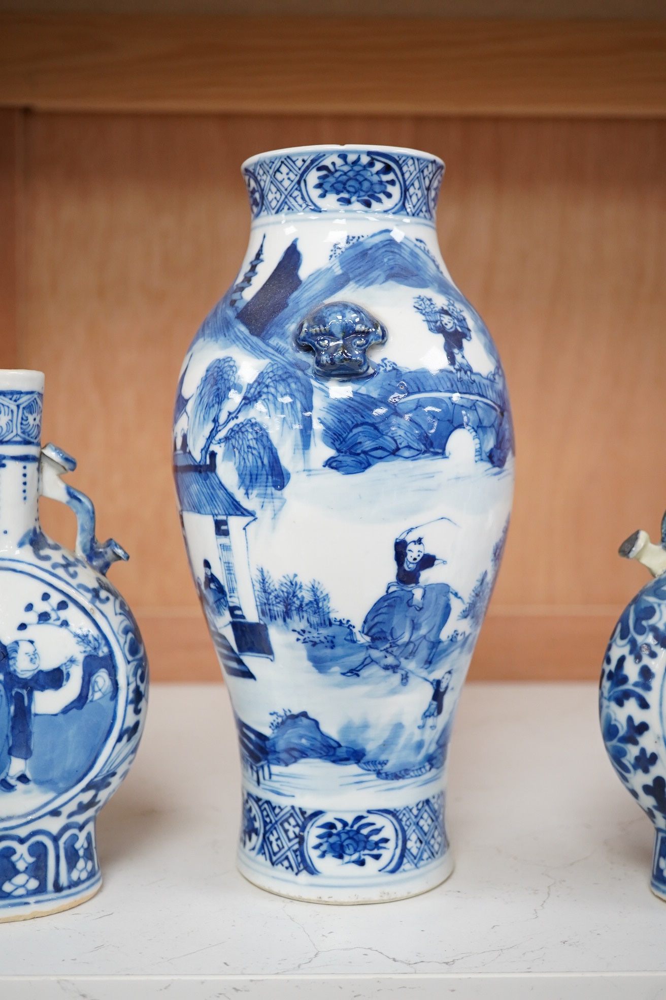 Late 19th century Chinese vases; pair of small Chinese blue and white moon flasks and a larger Chinese blue and white landscape vase, larger vase 22cm high. Condition - one moon flask handle restored, other items fair